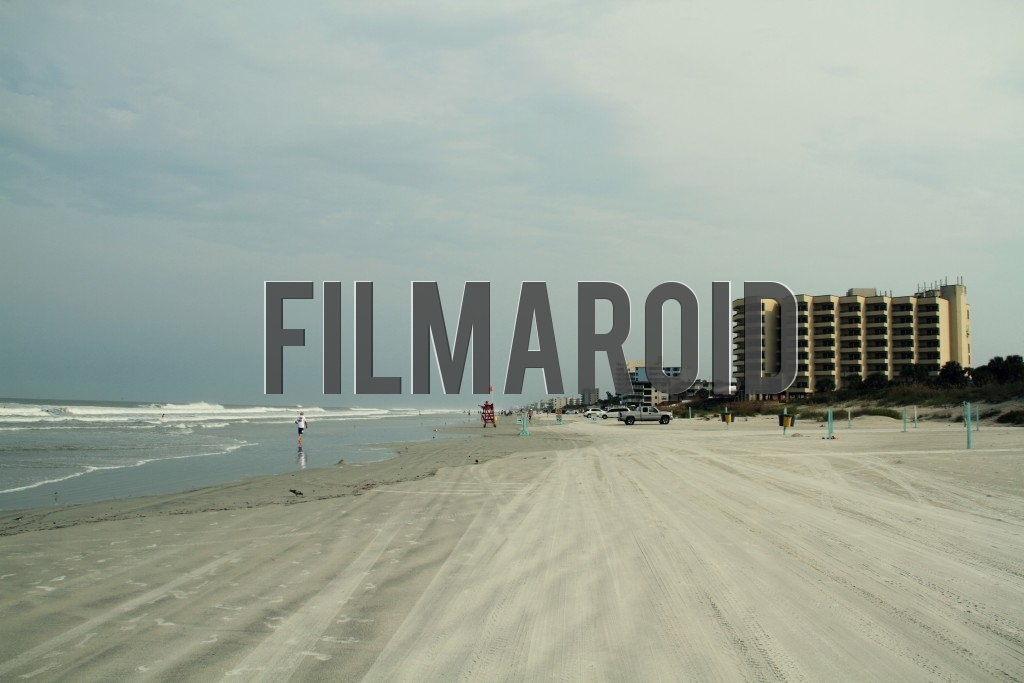 Landscape of a beach in Florida with waves buildings and people seen far in the distance