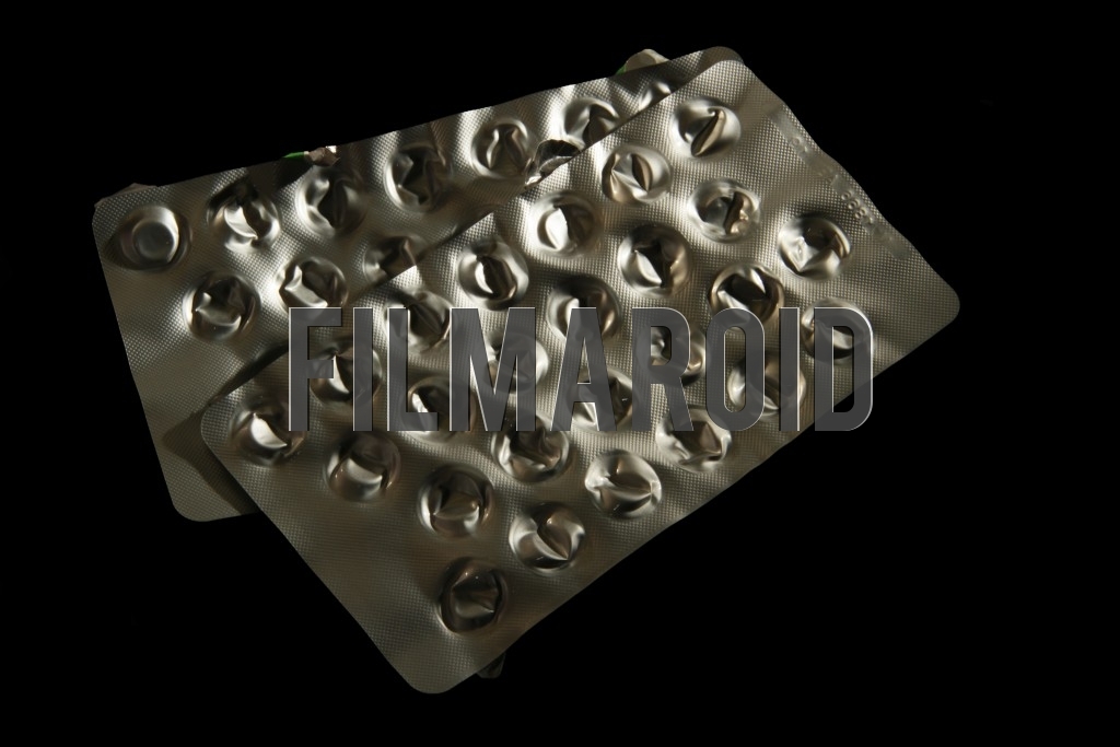 An isolated pair of empty pack of pills - A pair of isolated empty shiny aluminum packs of pills against a pitch black background