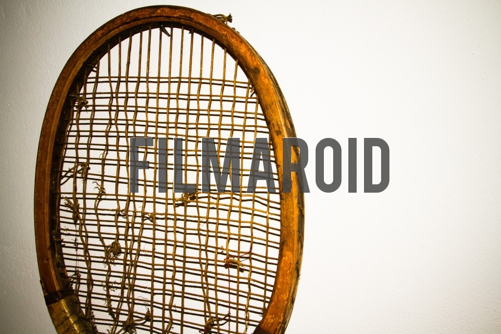 Detail view of an old wooden tennis racket frame with broken strings