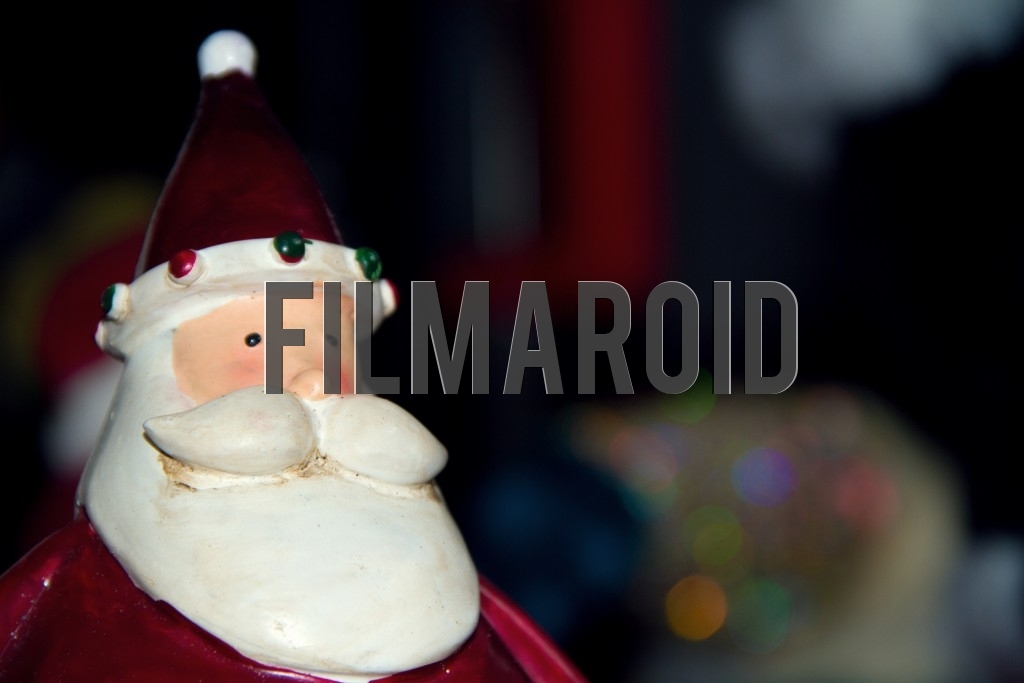 A closeup of a resin Santa Claus figure and colorful bokeh background