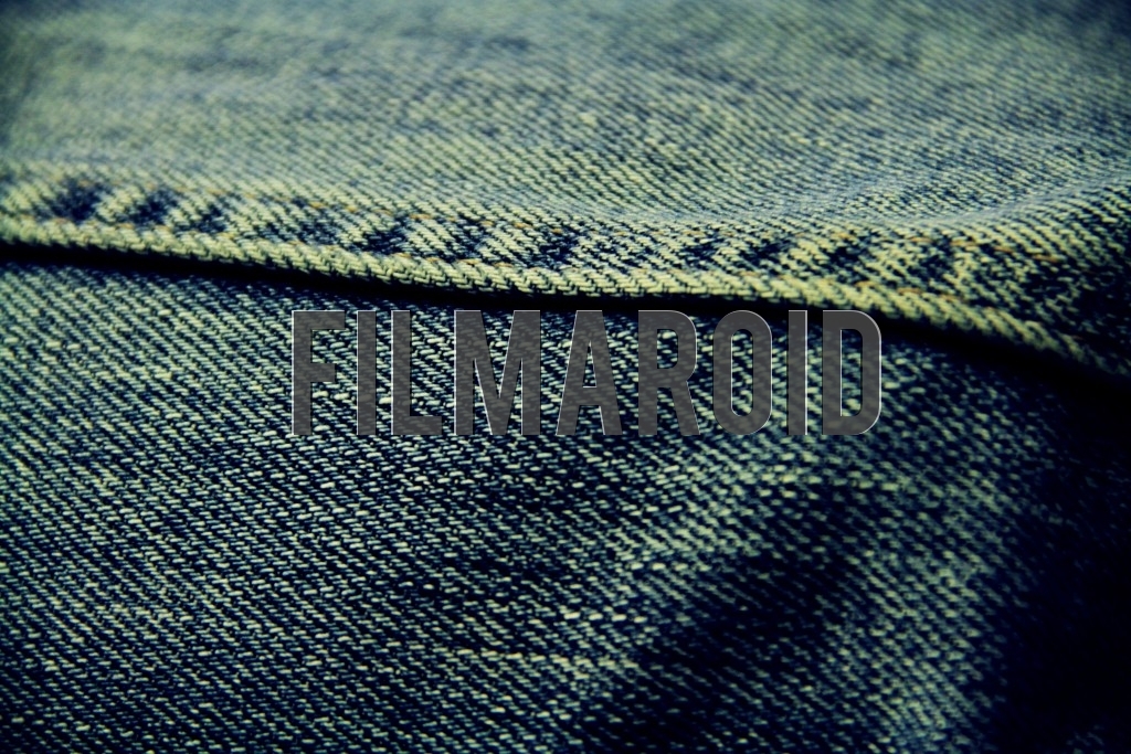 Closeup of an old blue denim fabric with sewing yellow stitches