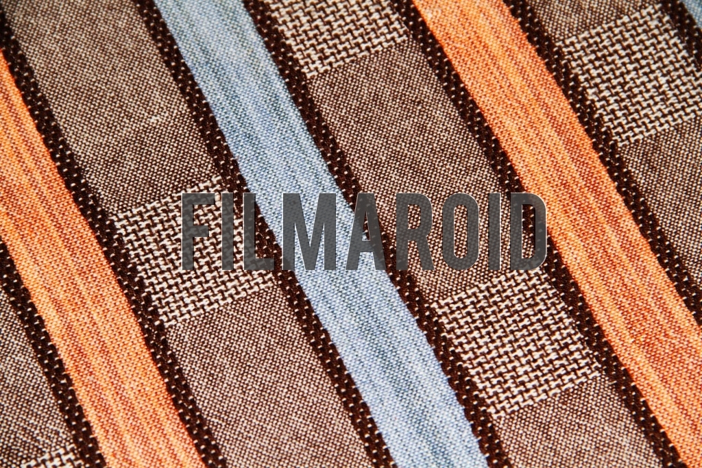 A striped fabric with yellow orange blue and brown tones and squared pattern texture