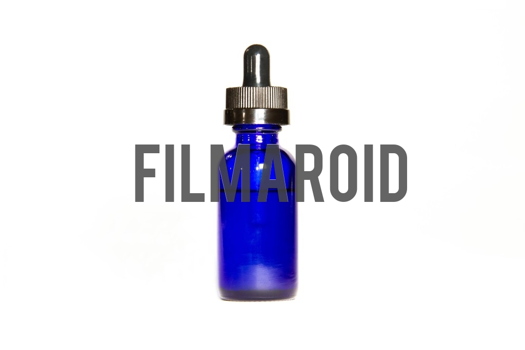 Beautiful cosmetic blue dropper glass bottle with closed lid isolated against white background