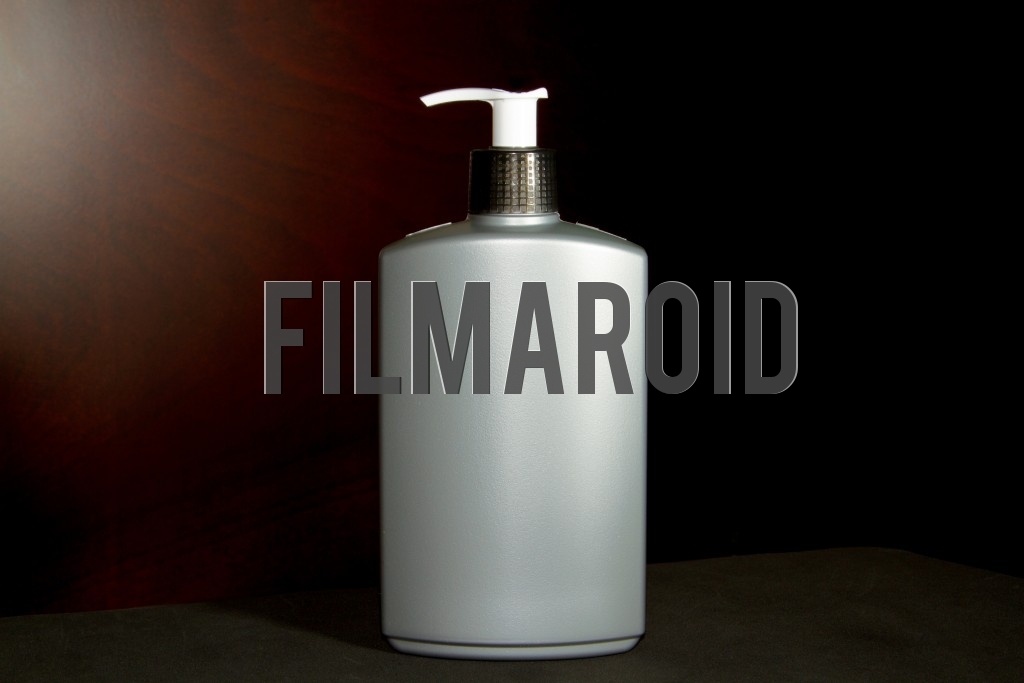 Isolated large gray plastic bottle ideal for body lotion or hands gel against a wooden background